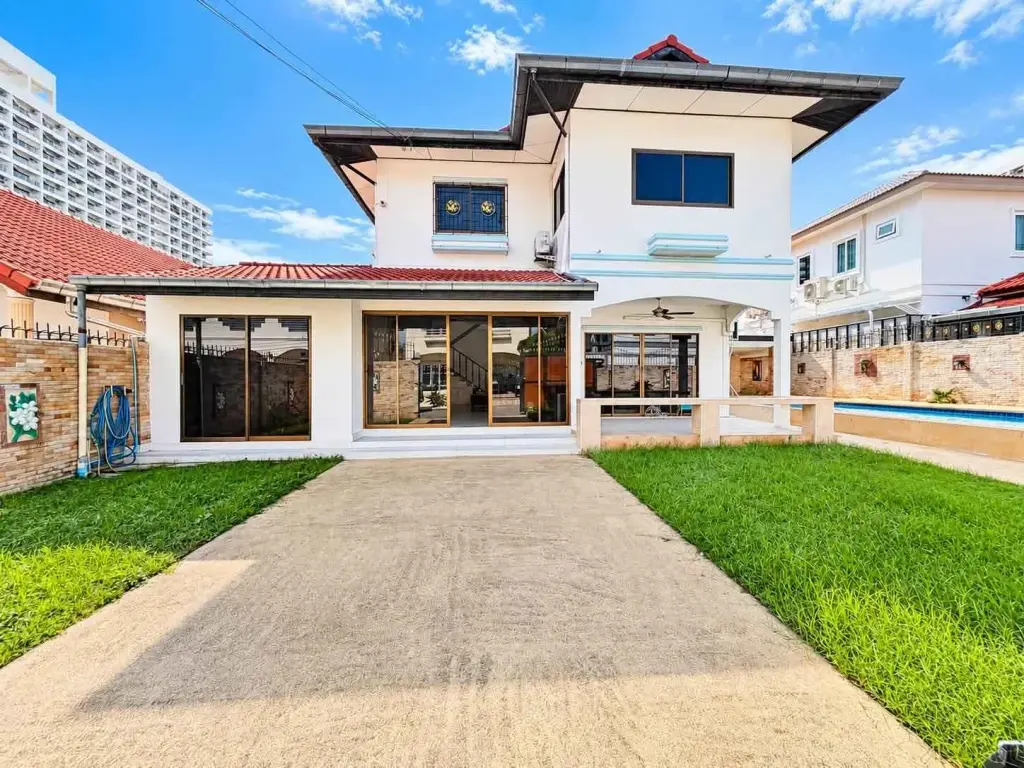 4 Bedroom House for Rent in Jomtien two-story exterior with lawn, driveway, and private pool area