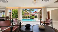 5 Bedroom House for Sale in Jomtien living room with leather chairs opening to pool and garden