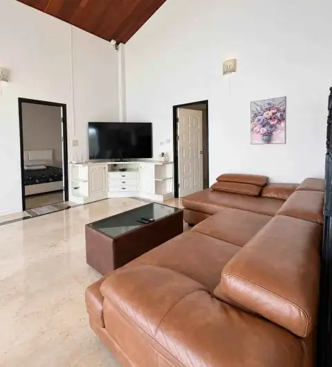 6 Bedroom House for Rent in Jomtien open-plan living area with wood-paneled ceiling and TV console