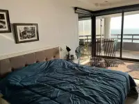 1 Bedroom Condo for Sale at Jomtien Plaza Condotel bed with teal comforter facing floor-to-ceiling sea view windows