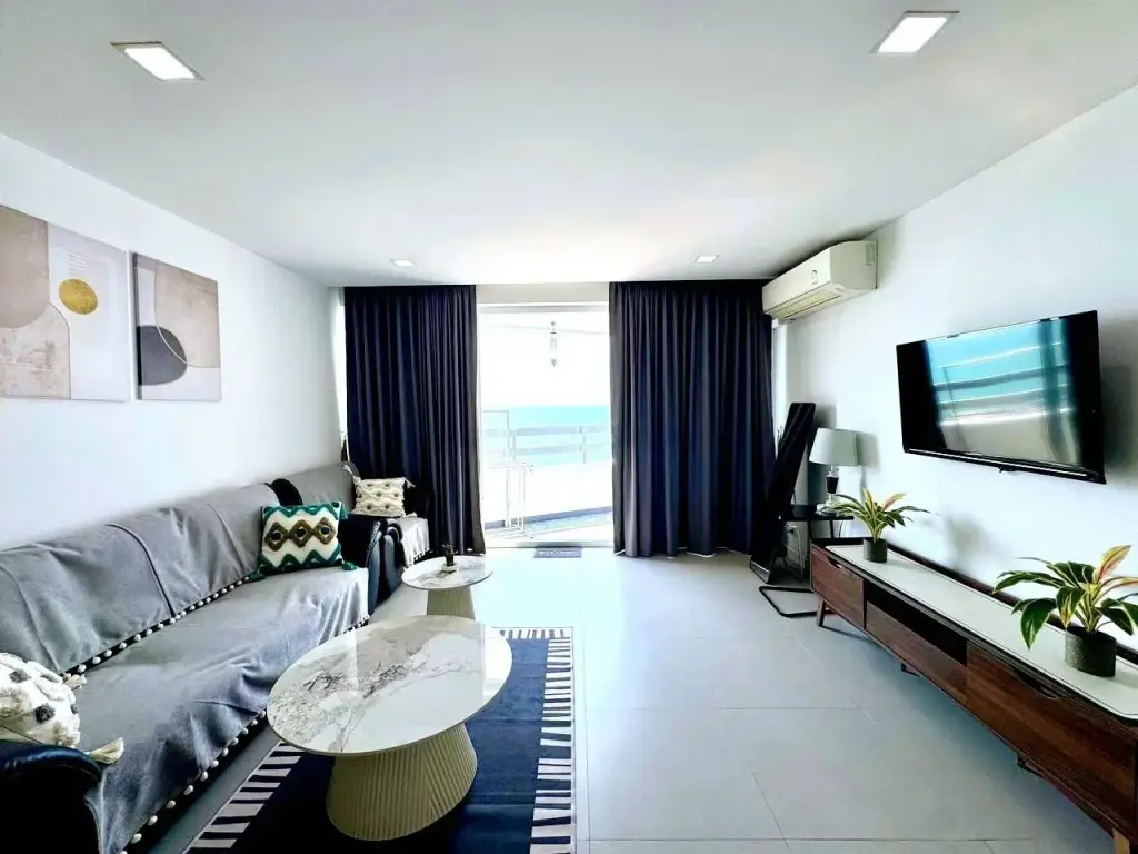 Studio Condo for Rent at Jomtien Plaza Condotel living area with gray sofa, TV console, and sea-view balcony