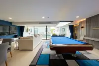 1 Bedroom Condo for Sale at Gardenia Pattaya recreation lounge with blue pool table, white sofa, TV wall and floor-to-ceiling balcony windows