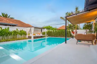 Srisuk Villa private swimming pool with outdoor daybed, lush green plants, and a shaded seating area.