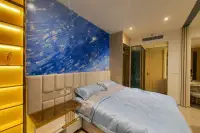 1 Bedroom Condo for Sale & Rent at Arom Wongamat king-size bed with blue abstract mural, gold backlit shelving unit, and glass wardrobe