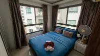 2 Bedroom Condo for Sale at Arcadia Beach Resort bedroom with blue bedding and large windows overlooking buildings