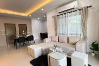 3 Bedroom House for Sale in Nong Prue living room with L-shaped sofa, coffee table, and dining area beyond.