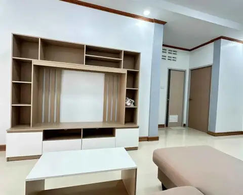 2 Bedroom Townhouse for Sale in East Pattaya empty living area with wooden entertainment unit and hallway doors
