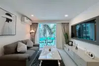 1 Bedroom Condo for Sale at City Center Residence bright living room with flat-screen TV grey sofa and sliding balcony doors