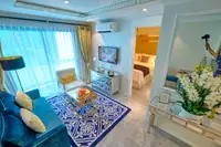 1 Bedroom Condo for Sale at Seven Seas Le Carnival: overhead view of living area, blue sofa, patterned rug, TV, and dining nook.