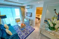 1 Bedroom Condo for Sale at Seven Seas Le Carnival: living room with blue sofa, patterned rug, TV, and view into the bedroom.