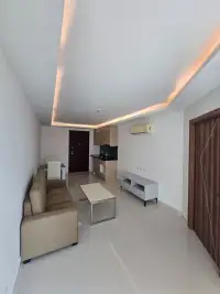 1 Bedroom Condo for Sale at Laguna Beach Resort 3 (The Maldives) living room with beige sofa and kitchenette with cove lighting