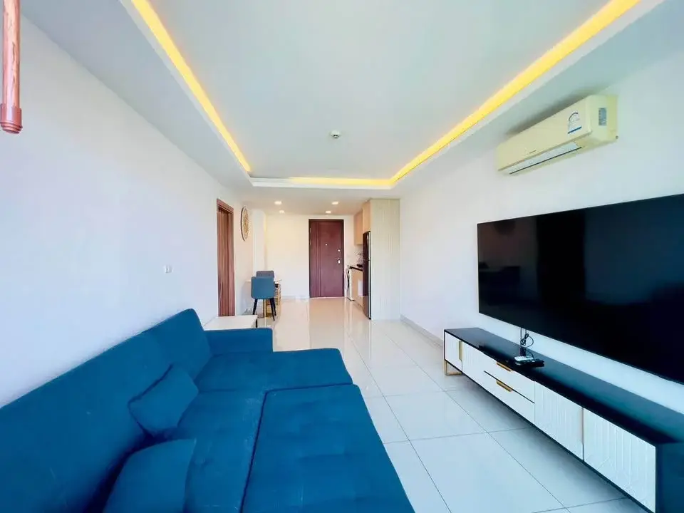 1 Bedroom Condo for Sale at Laguna Beach Resort 3 (The Maldives) living room with blue sofa and wall-mounted TV