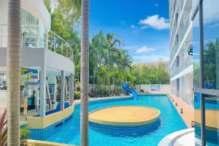 Laguna Beach Resort 1 swimming pool with a blue water slide, circular shallow area, and surrounding palm trees.