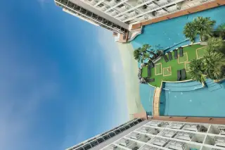 Laguna Beach Resort 1 overhead view of the lagoon pool, artificial beach, and sun loungers on a green island.