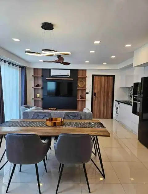 2 Bedroom Condo for Rent at Laguna Beach Resort 2 dining area with wooden table, TV wall unit, and kitchen view