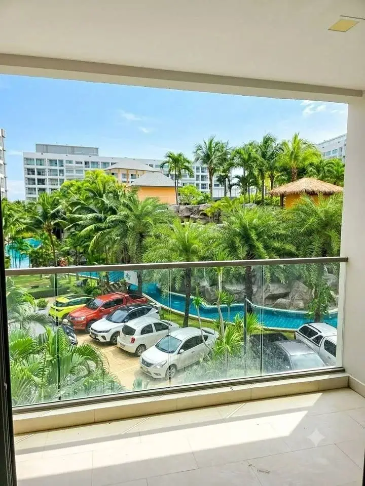 Studio Condo for Sale at Laguna Beach Resort 3 (The Maldives) balcony view of pool, palm trees, and parking area