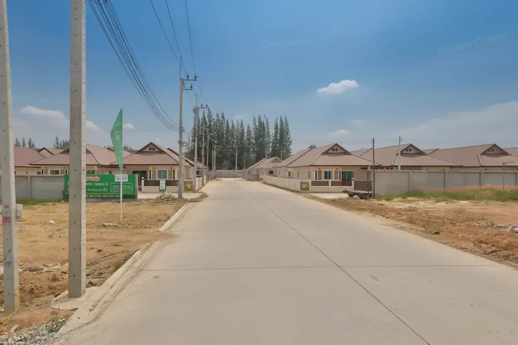 Lapatrada Village 5 residential street with rows of single-story houses, power lines, and a green real estate sign.