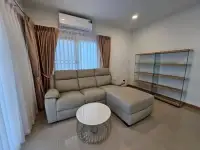 4 Bedroom House for Rent at Life in the Garden Rongpo - Motorway living room with grey sectional sofa and glass shelving unit
