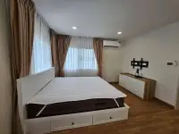4 Bedroom House for Rent at Life in the Garden Rongpo - Motorway bedroom with white bed frame and wooden TV console