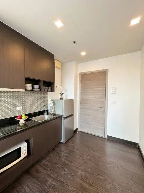 1 Bedroom Condo for Sale at Pattaya Posh kitchenette with dark cabinetry and entrance door