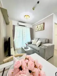 1 Bedroom Condo for Sale at Lumpini Park Beach Jomtien living area with dining table and pink floral centerpiece