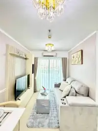 1 Bedroom Condo for Sale at Lumpini Park Beach Jomtien living room with TV unit, sofa, and balcony curtains