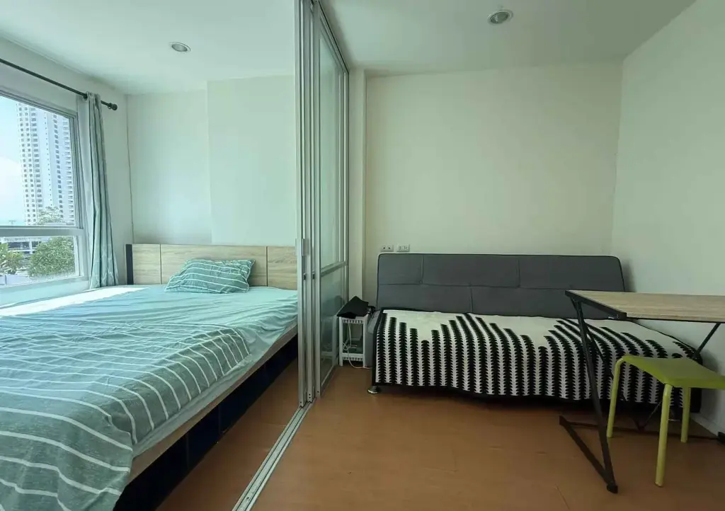 1 Bedroom Condo for Sale at Lumpini Seaview Jomtien bedroom with sliding glass partition, sofa bed, and desk
