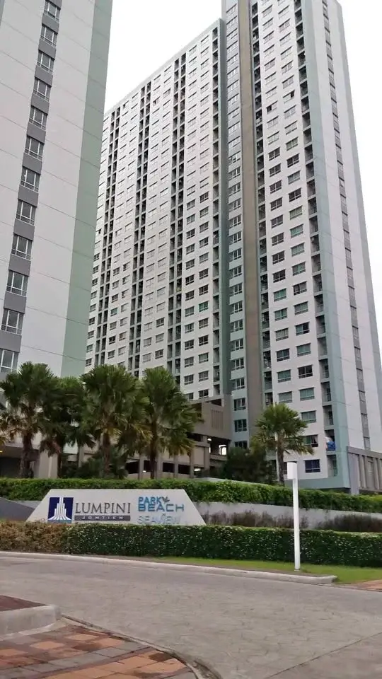 Lumpini Seaview Jomtien high-rise condo towers with entrance sign, palm trees, and driveway