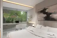2 Bedroom Condo for Sale at Celine Wongamat bedroom with king bed, wood accent wall, study nook, and panoramic green garden window