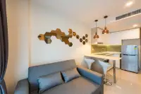 1 Bedroom Condo for Rent at The Riviera Jomtien living room with grey sofa, open kitchen, bar stools and copper pendant lights