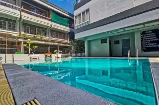 Hagone swimming pool with blue water, dark grey tiled edge, and surrounding buildings under a clear sky.