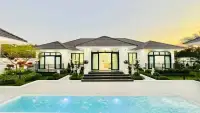 5 Bedroom House for Sale in Mabprachan exterior view of white villa with tiled roof, garden, and swimming pool at dusk