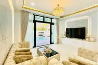 5 Bedroom House for Sale in Mabprachan living room with tufted cream sofas, crystal chandelier, and pool view