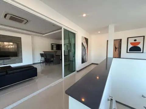 5 Bedroom House for Rent in Mabprachan open-plan living area with sofa, kitchen bar and abstract wall art