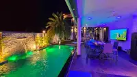 6 Bedroom House for Rent in Mabprachan night view of green-lit pool with waterfall wall and outdoor dining lounge