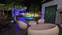 6 Bedroom House for Rent in Mabprachan poolside lounge area with wicker furniture and jacuzzi at night