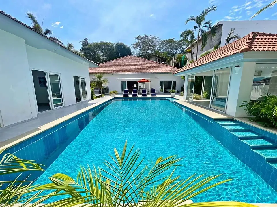 7 Bedroom House for Sale at Majestic Residence Pratumnak large tiled swimming pool surrounded by villa buildings and palm trees