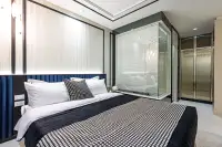 2 Bedroom Condo for Sale at Embassy Life master bedroom with blue velvet headboard and glass-enclosed en-suite bathroom