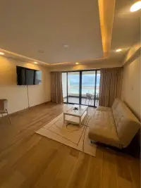1 Bedroom Condo for Sale at Metro Jomtien Condotel living area with sofa, TV, and panoramic sea view balcony
