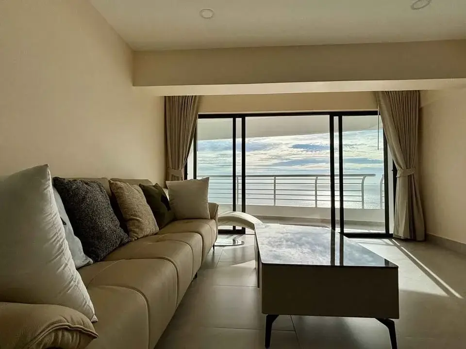 1 Bedroom Condo for Sale at Metro Jomtien Condotel living room with beige sofa and sea view balcony
