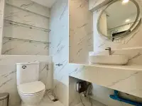 1 Bedroom Condo for Sale at Metro Jomtien Condotel marble bathroom with toilet, round mirror and vessel sink