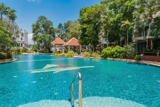 Metro Jomtien Condotel large outdoor swimming pool with colorful mosaic patterns and surrounding lush greenery.