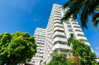 Thian Tong Condotel high-rise tower exterior viewed through palm trees against blue sky in Pattaya