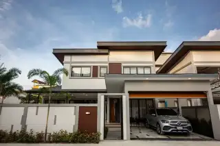 Zensiri Midtown Villas modern two-storey exterior with covered carport, Mercedes SUV, wooden front door and tropical landscaping