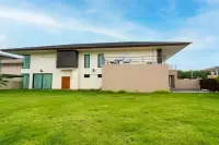 3 Bedroom House for Sale at Villa Asiatic rear exterior view with large green lawn and upper balcony with seating