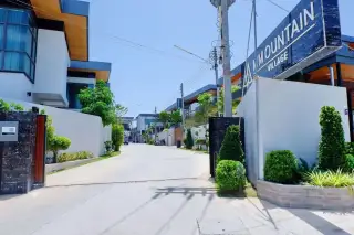 M Mountain Village gated entrance with wide internal road lined with modern two-storey houses