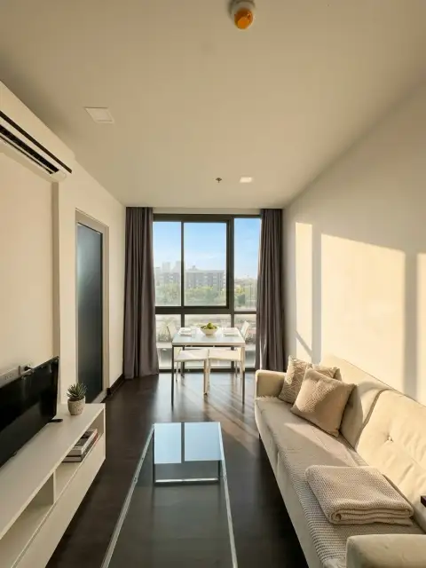 1 Bedroom Condo for Sale at Pattaya Posh bright living room with beige sofa and dining table by window