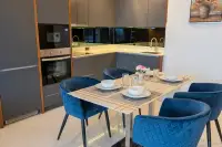 3 Bedroom Condo for Rent at Cosy Beach View modern kitchen and dining area with blue velvet chairs, built-in oven and grey cabinets