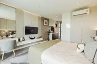 Studio Condo for Sale at The Coral Pattaya: Bedroom with full bed, side table, and view into the hallway.