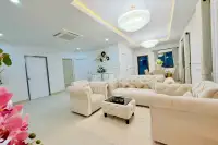 3 Bedroom House for Sale in Na Kluea living room with cream tufted sofas, crystal chandeliers, and dining area